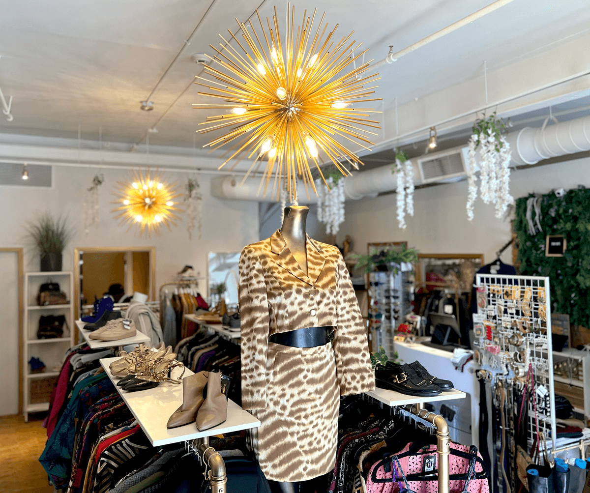 Inside TRiBE: a mannequin in an animal-print skirt suit under a gold starburst light, with shoes on shelves and clothing rails around it