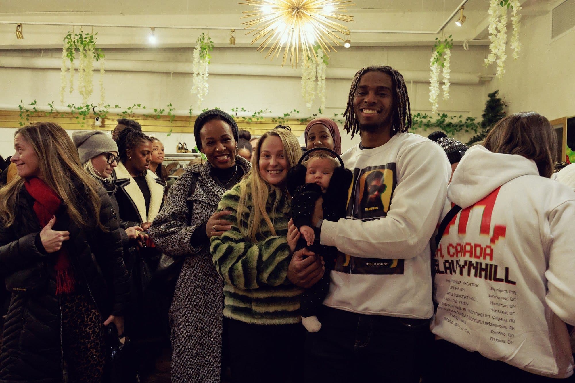 Smiling guests in the shop, one wearing a pop-up crewneck printed with a portrait of Ms. Lauryn Hill