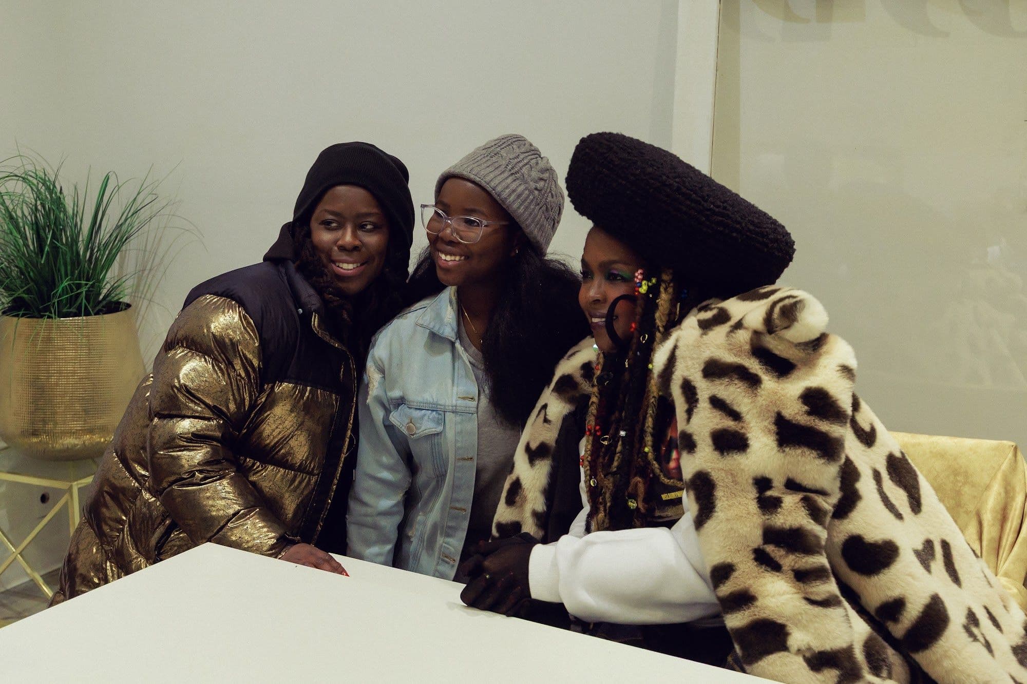 Ms. Lauryn Hill smiling with two guests at the shop counter during the pop-up